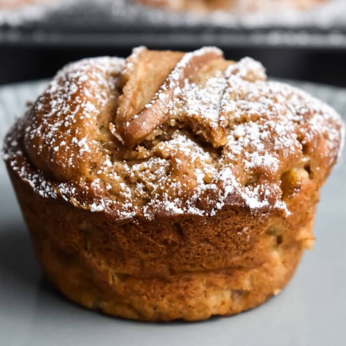 Jumbo Spiced Pear Muffins on a gray plate with a muffin tin behind